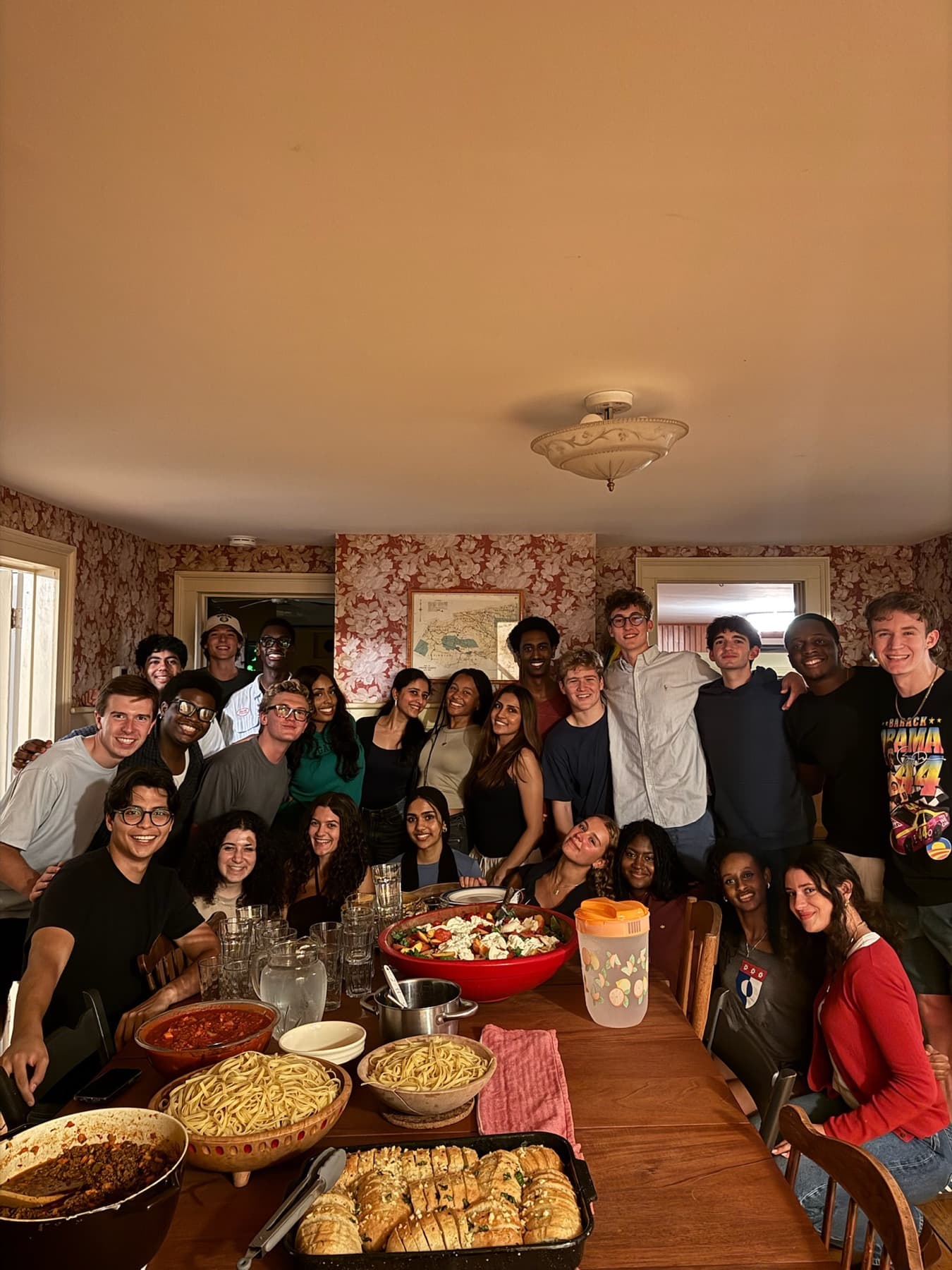 About twenty MUNTY members gathered around a dining table set with a shared meal.