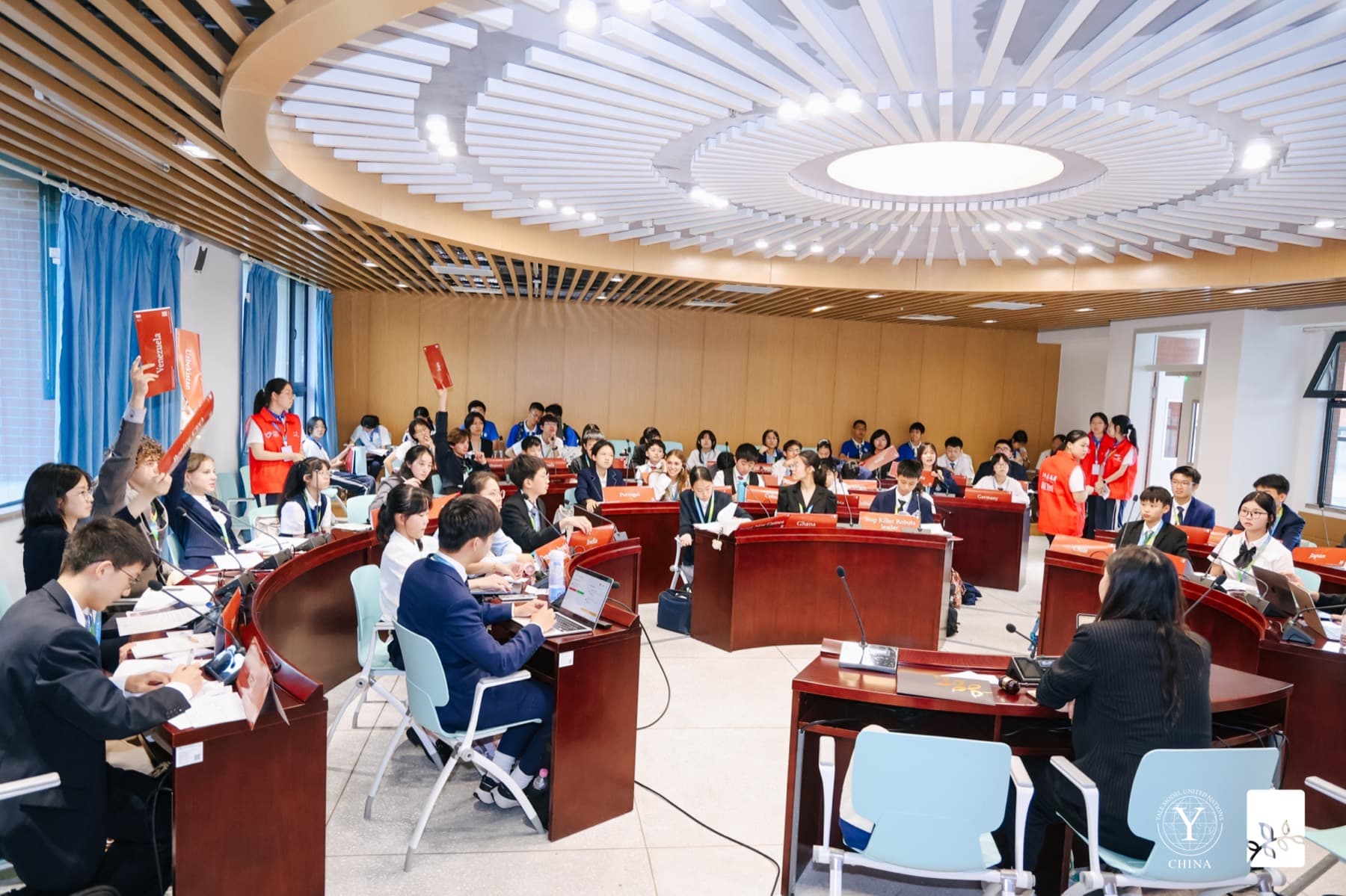 A circular committee chamber with a domed ceiling, delegates seated at curved desks around the floor.