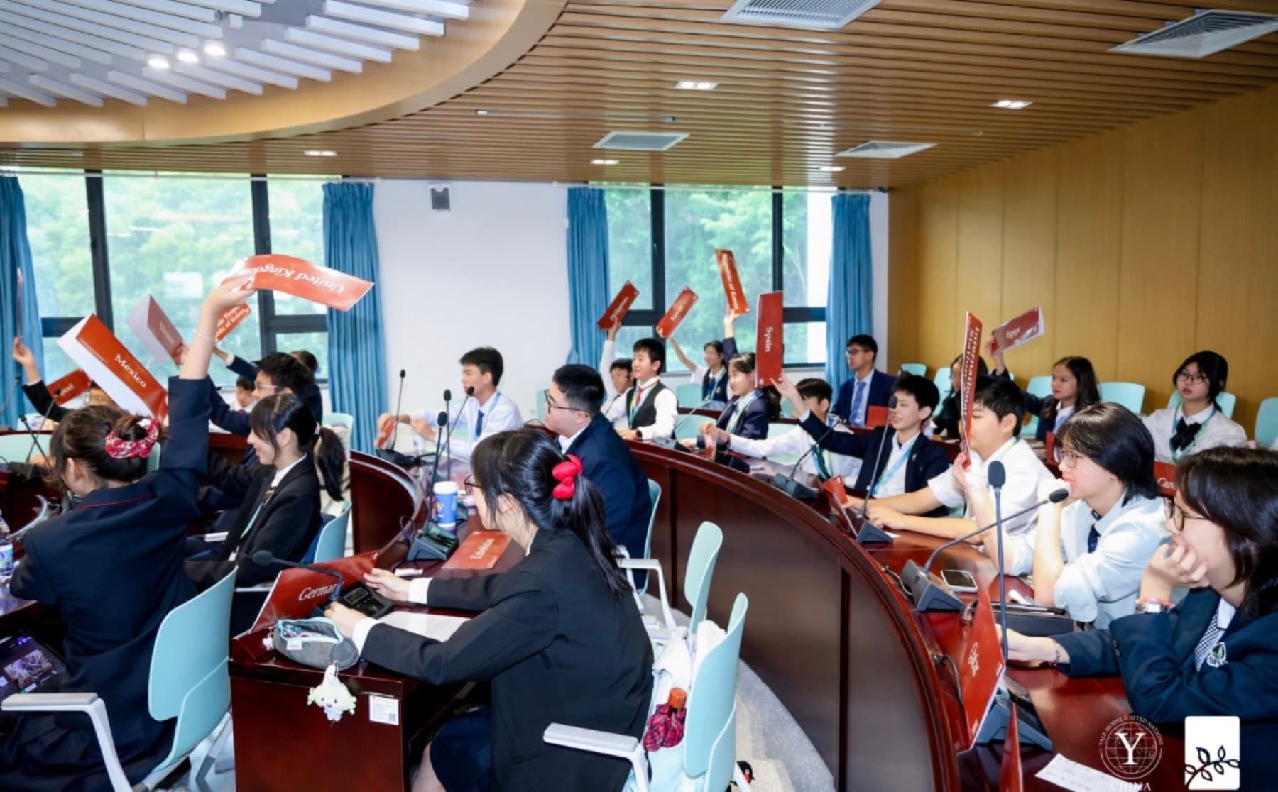 A tiered committee room full of delegates, several holding placards in the air.